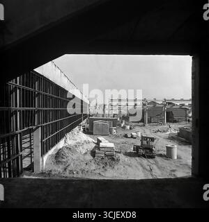 Construction à grande échelle de l'usine de film de chlorure de polyvinyle de Slavyansk dans la seconde moitié des années 1970, capturant le paysage industriel pendant l'ère de la stagnation : au premier plan se trouve une fosse de fondation avec des barres d'armature et des coffrages, tandis qu'une grue opère sur le site et les ateliers du futur géant chimique sont érigés, symbolisant la puissance industrielle et l'énergie créatrice d'un Donbass paisible Banque D'Images