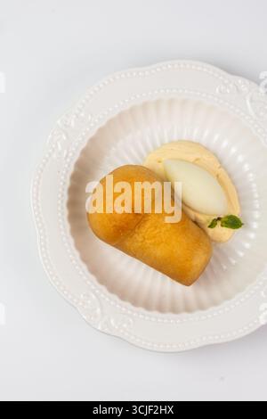 vue de dessus d'un dessert babka au rhum avec crème et sorbet en gros plan sur fond blanc. Banque D'Images