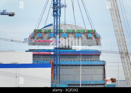 YANTAI, CHINE - 6 SEPTEMBRE 2025 - une grosse grue soulève la tête supérieure de la coque de sécurité de l'île nucléaire de l'unité 4 à la centrale nucléaire de Haiyang à Yantai, Shandong, Chine, le 6 septembre 2025. Banque D'Images