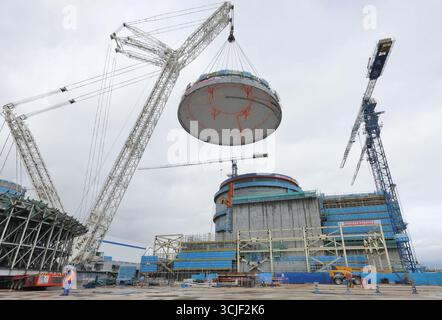YANTAI, CHINE - 6 SEPTEMBRE 2025 - une grosse grue soulève la tête supérieure de la coque de sécurité de l'île nucléaire de l'unité 4 à la centrale nucléaire de Haiyang à Yantai, Shandong, Chine, le 6 septembre 2025. Banque D'Images