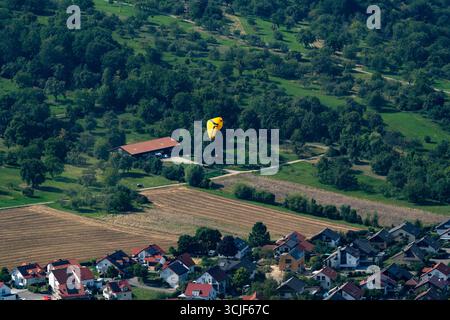 Parapente descendant au-dessus d'un village rural près de Breitenstein, Allemagne Banque D'Images