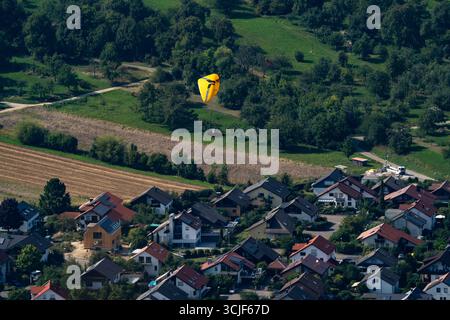 Parapente descendant au-dessus d'un village rural près de Breitenstein, Allemagne Banque D'Images