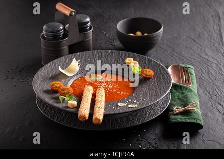 Soupe de tomates élégante comme nourriture de haute qualité dans un restaurant sophistiqué. Soupe de tomates avec une décoration exquise. Banque D'Images
