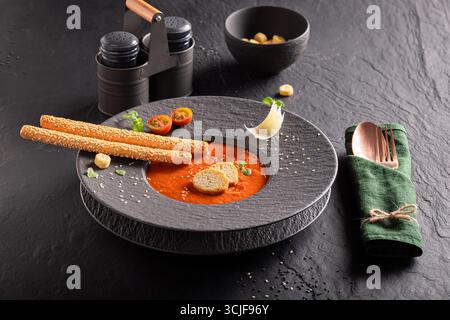 Soupe de tomate exclusive comme plat raffiné dans un restaurant. Soupe de tomates avec une décoration exquise. Banque D'Images