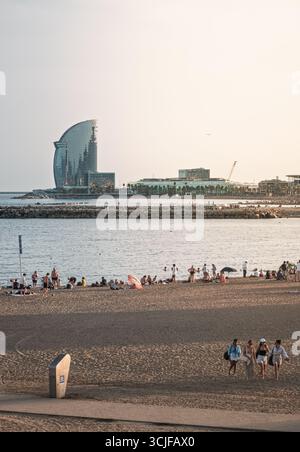 Barcelone, Espagne. 06 septembre 2025, touristes se relaxant sur la plage de Barceloneta avec l'hôtel W Barcelona en arrière-plan Banque D'Images