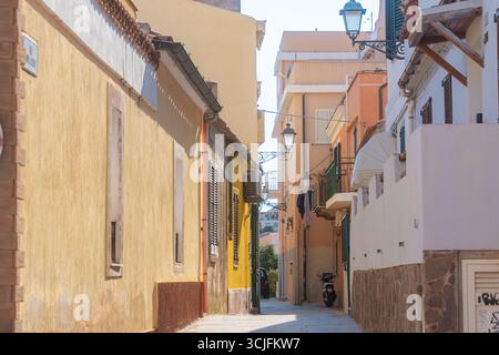 Pittoresque ruelle étroite bordée de bâtiments colorés dans un village méditerranéen. La lumière du soleil améliore les teintes vibrantes, créant un cadre pittoresque et accueillant Banque D'Images