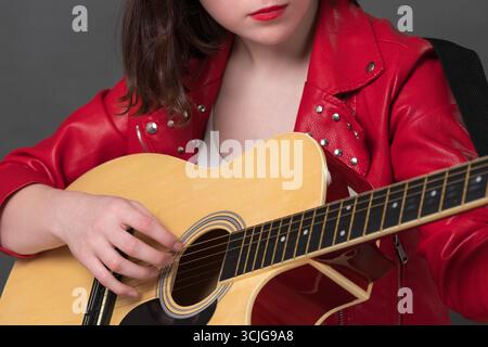 Vue rapprochée des doigts de la guitariste tapant habilement les cordes de son instrument de musique, créant des sons mélodiques qui ajoutent à l'énergie vibrante de Banque D'Images