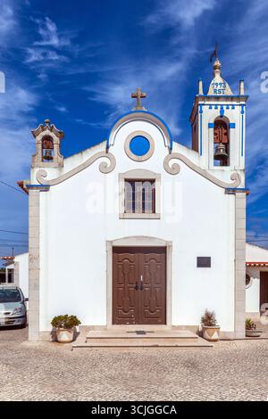 Une charmante chapelle blanche d'Igreja da Assenta avec des accents bleus, des détails ornés, et un clocher se dresse sous un ciel bleu vif, entouré de pots Banque D'Images