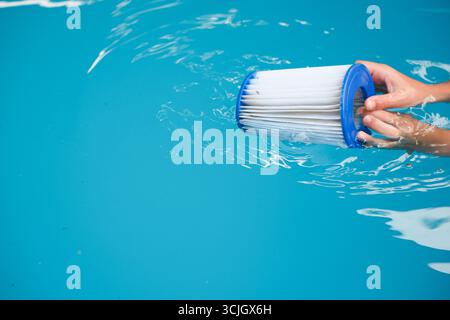 Сhild jouer avec la cartouche filtrante de piscine de remplacement dans la piscine. Cartouche filtrante facile à changer, qualité de l'eau. Banque D'Images