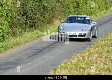 Voiture de sport argentée conduisant sur une route de campagne panoramique en plein jour. Shere Hill Climb, East Clandon, Guildford Banque D'Images