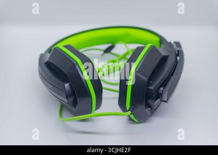 Casque de jeu filaire moderne avec bandeau réglable en noir et vert sur plateau blanc. Banque D'Images