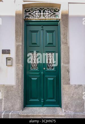 Élégante porte en bois vert avec grilles décoratives en fer blanc et tableau arrière orné, sertie dans un cadre en pierre. Le numéro 350 et un système d'interphone sont montés Banque D'Images