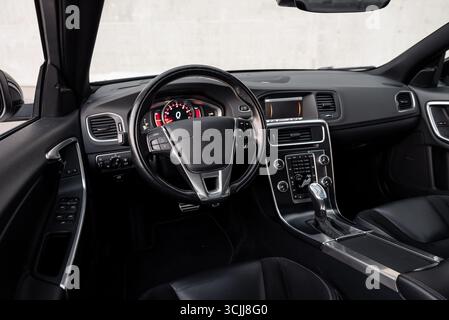 Intérieur de voiture moderne. Vue grand angle du cockpit de voiture : siège du conducteur, volant, console centrale et mur de béton en arrière-plan. Banque D'Images