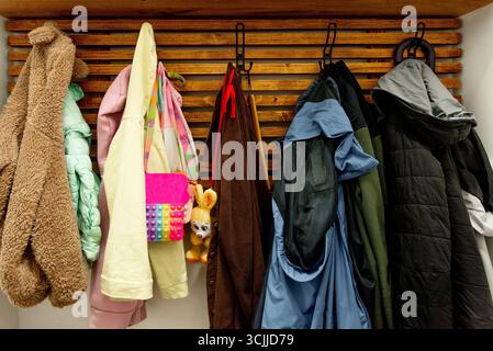 Vestes d'extérieur d'automne et manteaux suspendus sur des cintres dans une armoire en bois dans le couloir Banque D'Images