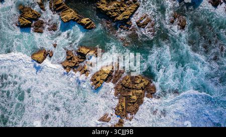 Plan aérien du littoral rocheux avec des vagues éclaboussant sur des pierres et une mer bleu vert paysage naturel puissant et vue panoramique sur la côte d'en haut Banque D'Images