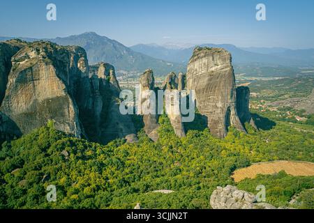 Vue panoramique sur les Météores en Grèce centrale avec de célèbres monastères construits sur des falaises au-dessus de la forêt verte et une large vallée avec des montagnes Banque D'Images