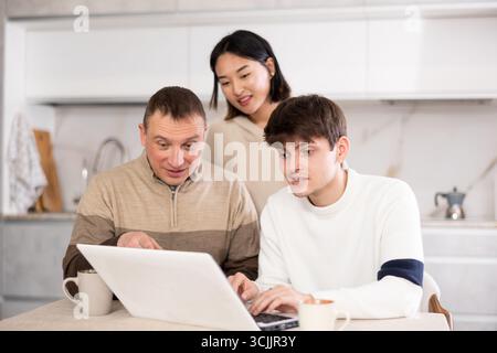 Une famille amicale regarde quelque chose ensemble sur Internet ou des chats vidéo via un ordinateur portable Banque D'Images