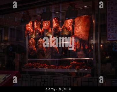 Diverses viandes sur une broche accrochée dans une vitrine d'un restaurant chinois et boucher à Chinatown dans le district de Soho, Londres, Angleterre, Royaume-Uni Banque D'Images