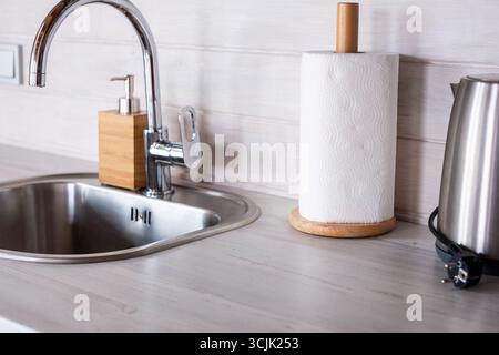 L'intérieur de la cuisine scandinave présente un design minimaliste avec un évier en acier inoxydable, des accents en bois et une bouilloire moderne, soulignant un a lumineux Banque D'Images