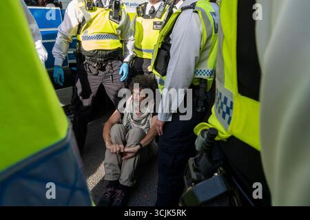 Un homme dans un keffiyeh, entouré de policiers, est arrêté pour avoir tenu une pancarte "je m'oppose au génocide, je soutiens l'action palestinienne". Palestine action Protest. Banque D'Images
