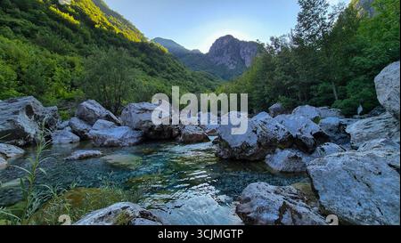 Ruisseau avec des pierres au premier plan le long du sentier Blue Eye près de Theth, avec les Alpes albanaises en arrière-plan, Albanie. Banque D'Images