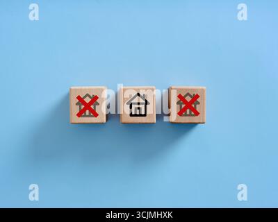 Cubes en bois avec des icônes de maison, deux barrés, suggérant de choisir la bonne propriété ou de prendre une décision dans l'immobilier Banque D'Images