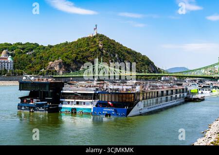 Bateaux amarrés sur le Danube à Budapest avec la colline Citadella et le pont de la liberté en arrière-plan. Banque D'Images
