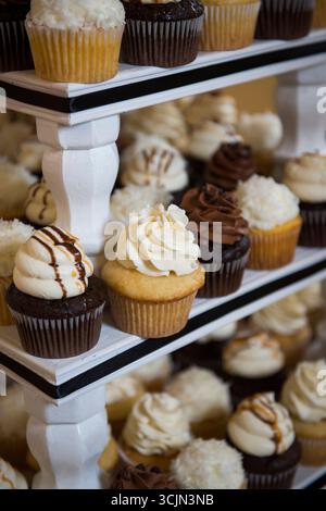 Assortiment de cupcakes givrés sur un support blanc à gradins Banque D'Images