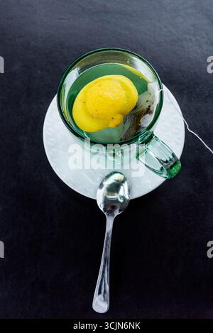 Boisson de thé noir saine à base de plantes emballée avec des bières de citron dans une tasse en verre sur la table Banque D'Images