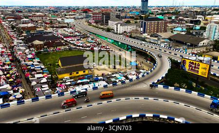 Vue aérienne d'un paysage urbain animé de Lagos avec un marché animé s'étendant sous une autoroute surélevée, Isaac Boro Park, Port Harcourt, Rivers State, Nigeria. Banque D'Images