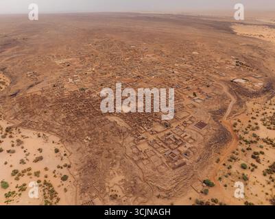 Vue aérienne de la ville antique se déploie dans des tons terreux discrets, bâtiments nichés au milieu du vaste paysage désertique ondulé, Ouadane, Adrar, Mauritan Banque D'Images