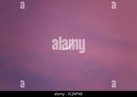 Le premier croissant de lune, également connu sous le nom de croissant de lune initial, un petit ruban de lumière à l'ouest au coucher du soleil, en forme de « C » renversé Banque D'Images