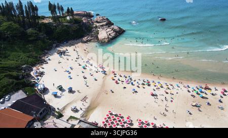 Vue aérienne de la plage de Joaquina à Florianopolis, Santa Catarina, bondé de gens avec de nombreux parasols sur le sable par une journée d'été ensoleillée Banque D'Images
