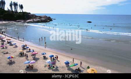 Vue aérienne de la plage de Joaquina à Florianopolis, Santa Catarina, bondé de gens avec de nombreux parasols sur le sable par une journée d'été ensoleillée Banque D'Images