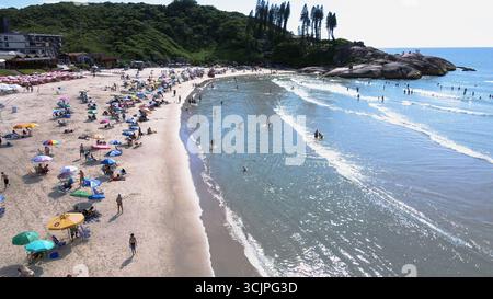 Vue aérienne de la plage de Joaquina à Florianopolis, Santa Catarina, bondé de gens avec de nombreux parasols sur le sable par une journée d'été ensoleillée Banque D'Images