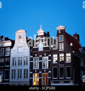 Maisons de canal hollandaises traditionnelles avec façades étroites et toits à pignons sous un ciel clair du soir. Banque D'Images