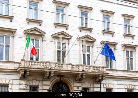 Drapeaux italiens et européens sur la façade du bâtiment historique. Des drapeaux italiens et de l'Union européenne sont suspendus à l'extérieur d'un bâtiment classique du gouvernement européen ou de l'ambassade Banque D'Images