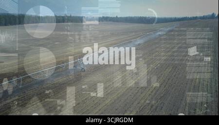 Plate-forme d'irrigation à pivot central étirant arrosant un champ labouré sur des terres agricoles, avec superpositions HUD numériques Banque D'Images