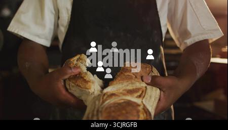 Arracher le pain artisan à part boulanger portant un tablier au comptoir en bois dans la boulangerie, avec une lumière chaude Banque D'Images