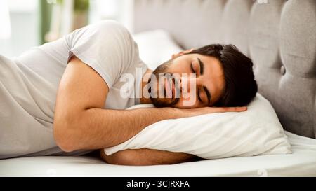 Sommeil confortable. Homme arabe millénaire qui dormait paisiblement et voit des rêves sucrées, allongé dans un lit confortable et un oreiller enrageant Banque D'Images