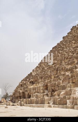 Gros plan de la Grande Pyramide de Gizeh, Égypte, montrant des blocs de pierre massifs de l'architecture ancienne sous ciel clair, merveille historique du monde. Banque D'Images