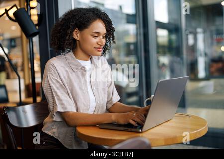 Femme concentrée travaillant sur ordinateur portable dans Modern CAF Banque D'Images