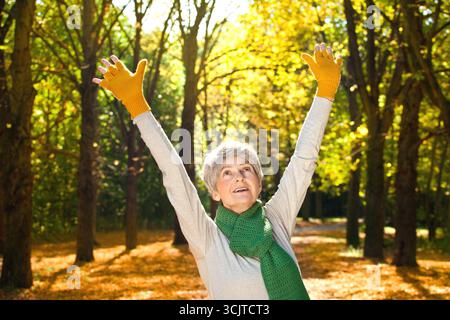 femme âgée joyeuse faisant des exercices de fitness en plein air en automne, portrait mi-long Banque D'Images