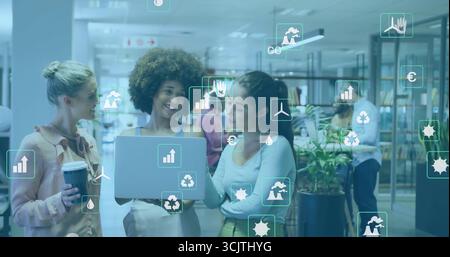 Trio collaborateur de femmes examinant les données sur l'écran d'ordinateur portable à la bibliothèque ouverte, avec tasse à café Banque D'Images