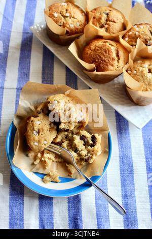 Muffin à la banane fraîche cuit à la maison sur une assiette de cornouailles avec fourchette à gâteau sur un fond de tissu bleu côtier rayé. Banque D'Images