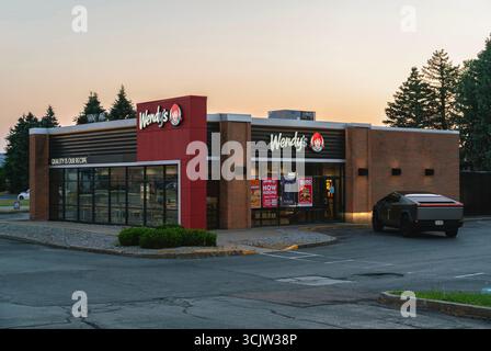 Utica, NY - 15 août 2025 : vue rapprochée au coucher du soleil d'un magasin Wendy's avec Tesla Cybertruck garé. Wendy's est un restaurant international de restauration rapide Banque D'Images