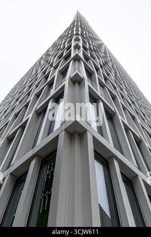 Vue spectaculaire en bas angle d'un gratte-ciel moderne mettant en valeur sa façade géométrique. La conception du bâtiment présente des lignes nettes et des fenêtres réfléchissantes, emp Banque D'Images
