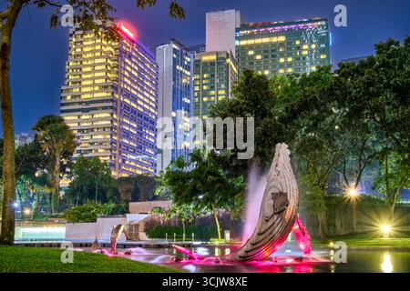 7 nov. 2019 - Kuala Lumpur, Malaisie : scène nocturne de la zone du parc KLCC avec des gratte-ciels lumineux et une fontaine connue sous le nom de baleine et dauphins avec des lumières colorées. Verdure luxuriante dans le parc de la ville, mélange coloré de nature, d'art et d'architecture urbaine. Banque D'Images