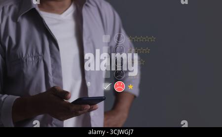 Avis client, jeune homme tenant main smartphone pour examiner et donne 1 étoile, avec de mauvais résultats de service, mauvais avis évalué juste 1 étoile option de commentaires Banque D'Images