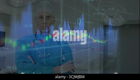 Chirurgien adulte debout croisant les bras, visualisant des graphiques financiers superposés en salle d'opération Banque D'Images